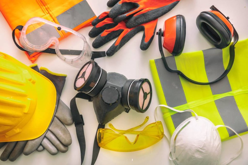 Work safety protection equipment flat lay. Industrial protective gear on white background, top view. Construction site health and safety concept